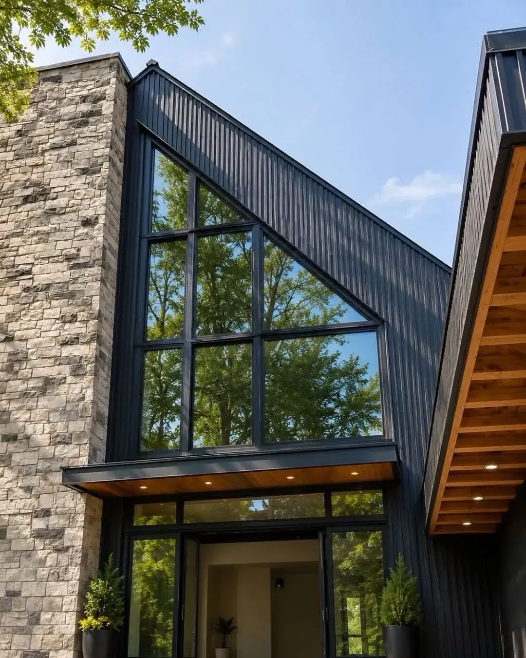 Modern black-clad home addition with a stone accent wall and floor-to-ceiling windows