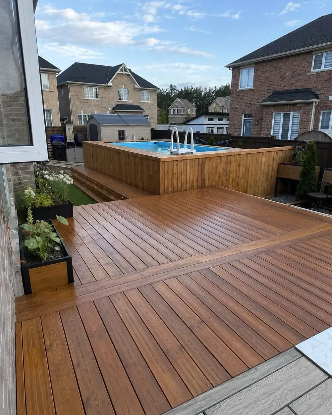 Multi-level stained wood deck surrounding an above-ground pool in a GTA backyard