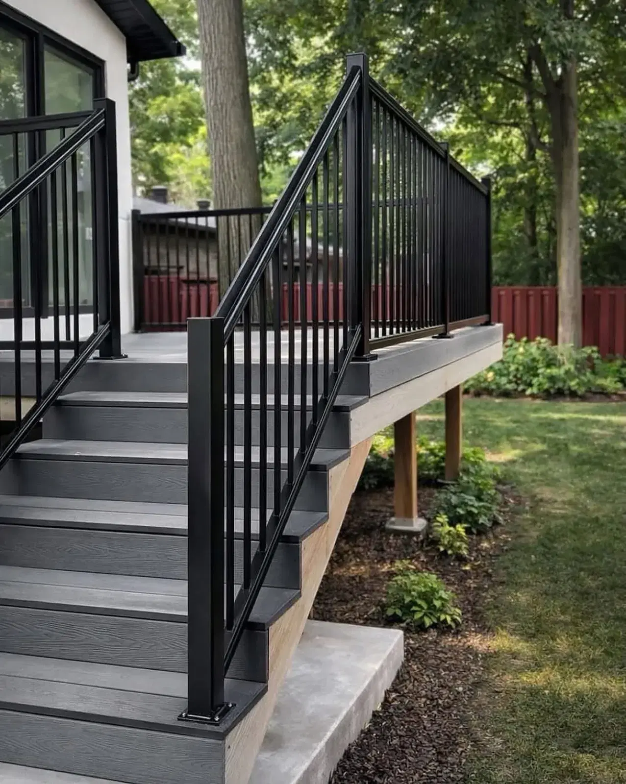 Grey composite deck with a black aluminum railing and staircase to the yard